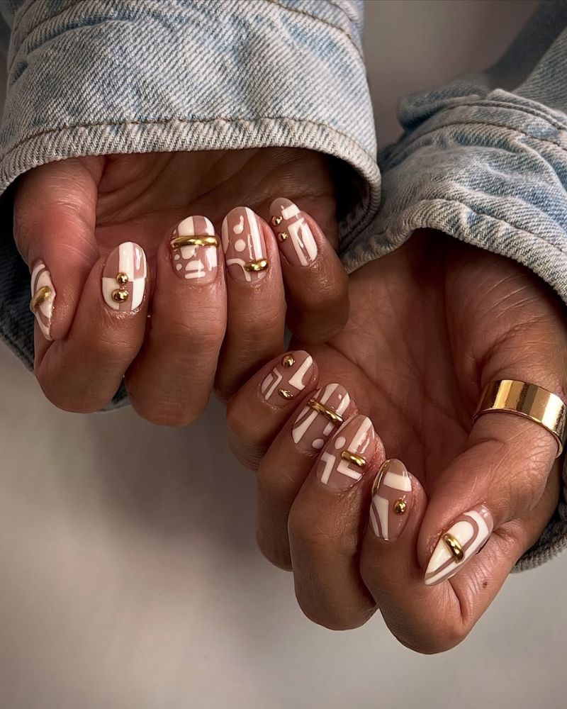 nail art abstrait blanc avec accents 3D dorés