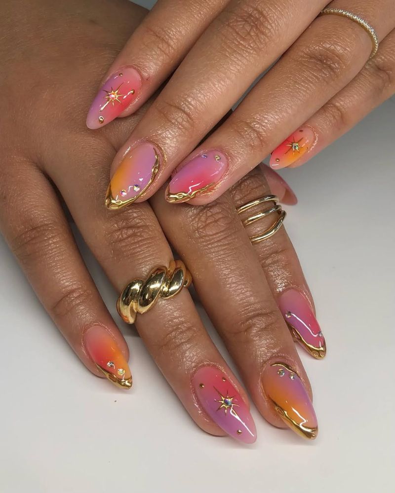 ongles ombrés rose, orange et violets avec accents dorés et nail art céleste