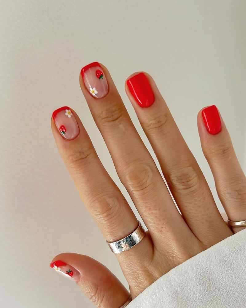 Ongles rouges courts avec un joli nail art fraise sur une french rouge