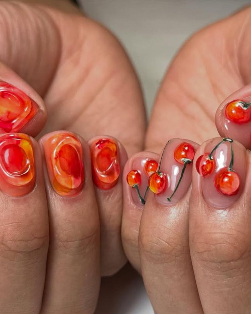 nail art cerises avec éléments 3D et nuances orange