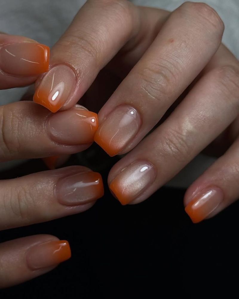 Manucure dégradée œil de chat du nude aux pointes orange