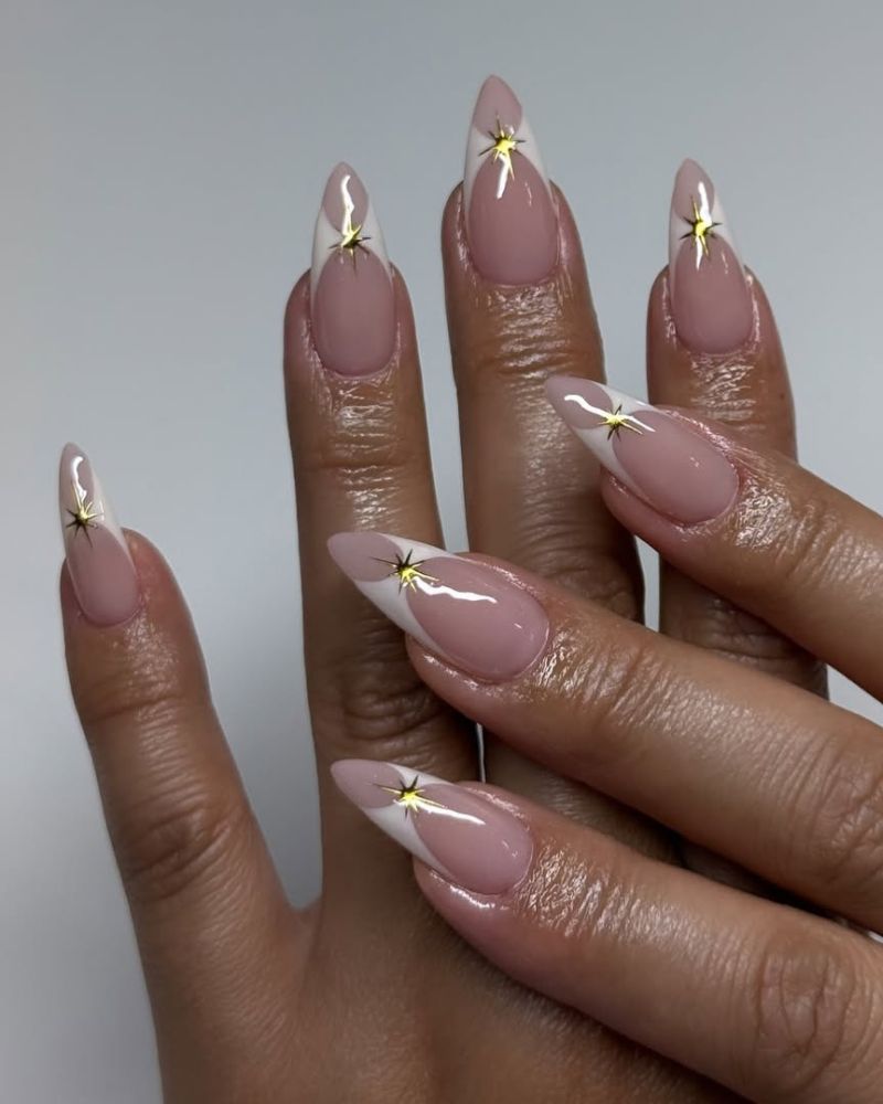 ongles stiletto avec manucure française modifiée et nail art étoiles dorées