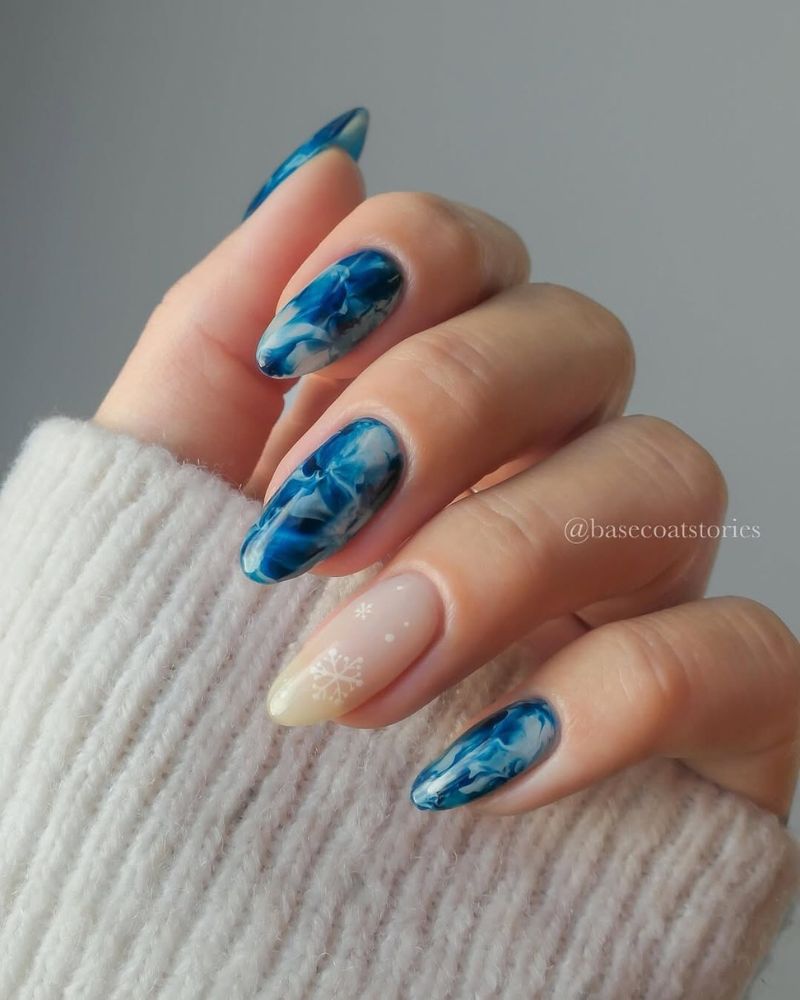 nail art d’hiver avec un design marbré blanc et bleu