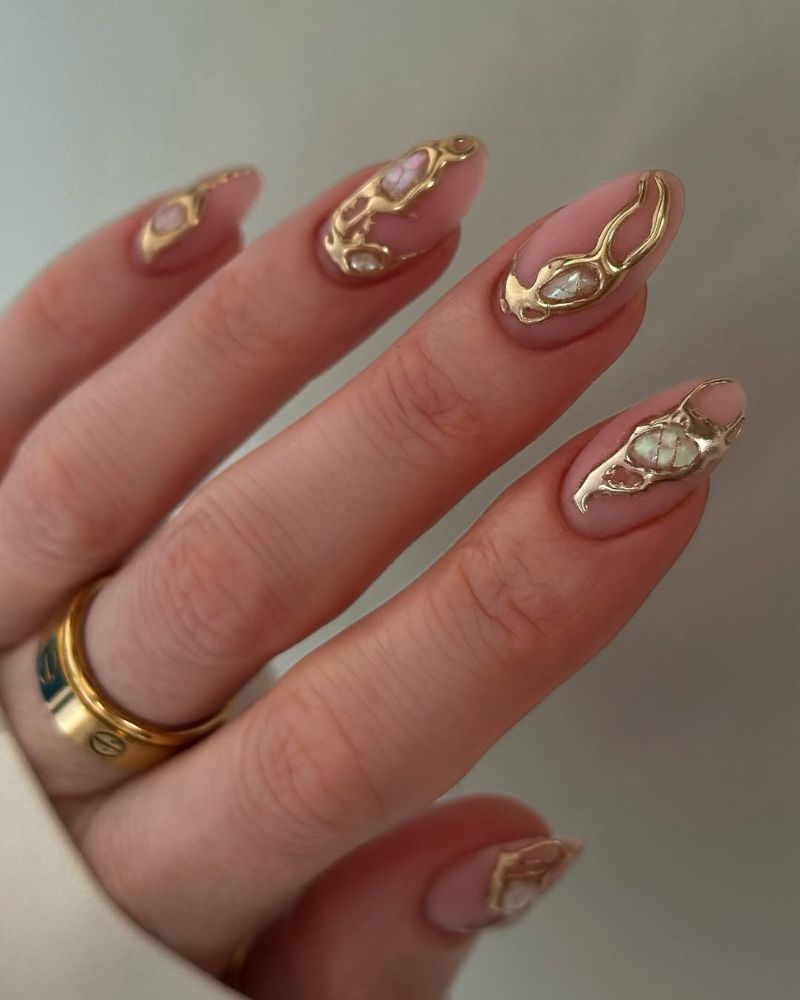 manucure mate nude avec nail art doré et pierres précieuses