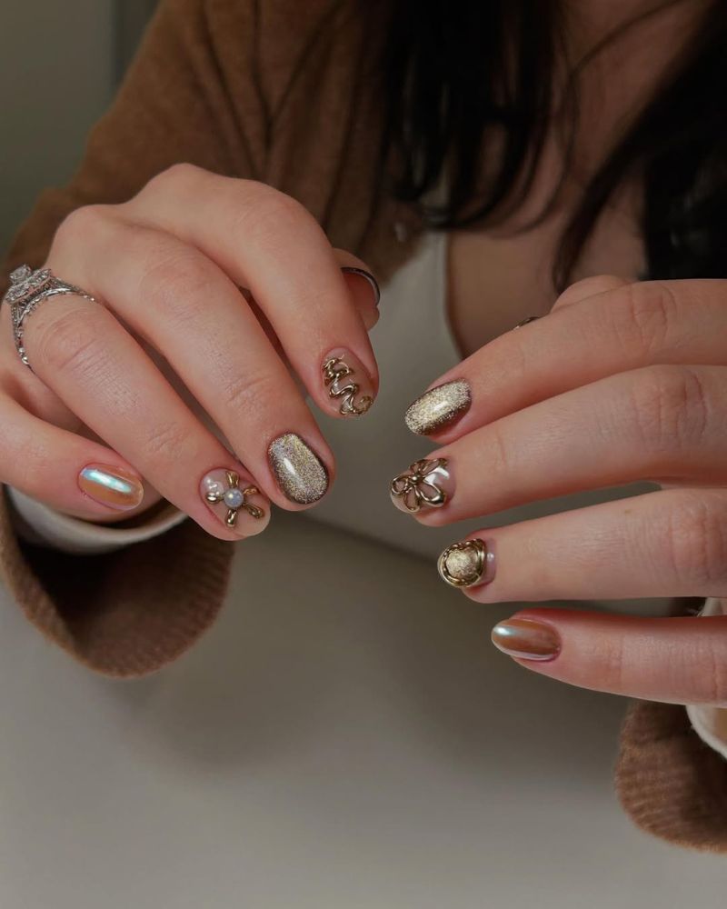 ongles courts dorés avec design œil de chat et nail art 3D