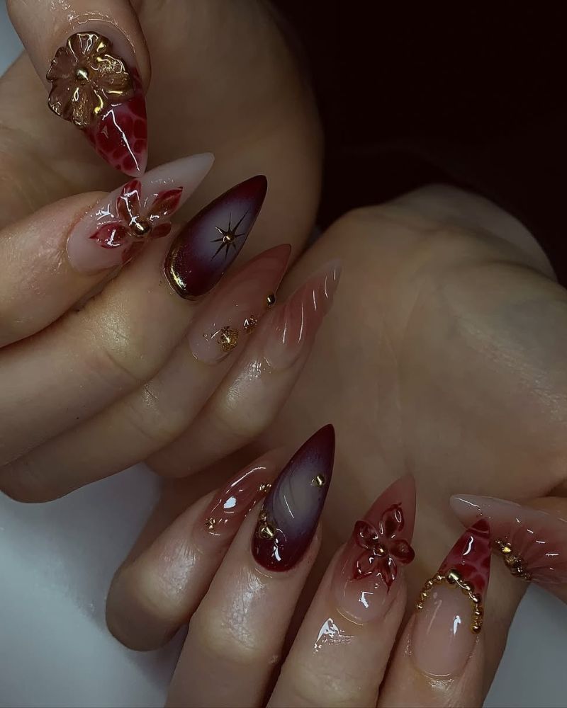 ongles stiletto longs avec détails or et nail art floral en 3D