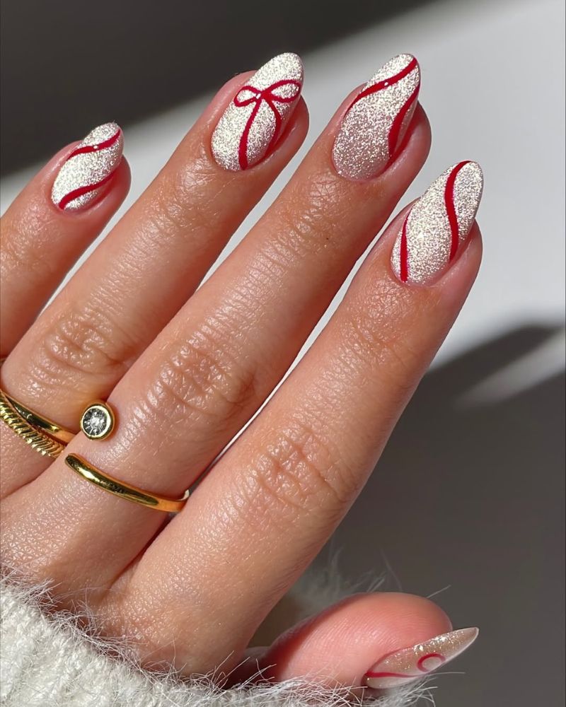 ongles œil de chat argentés avec nœud rouge en nail art pour une manucure festive