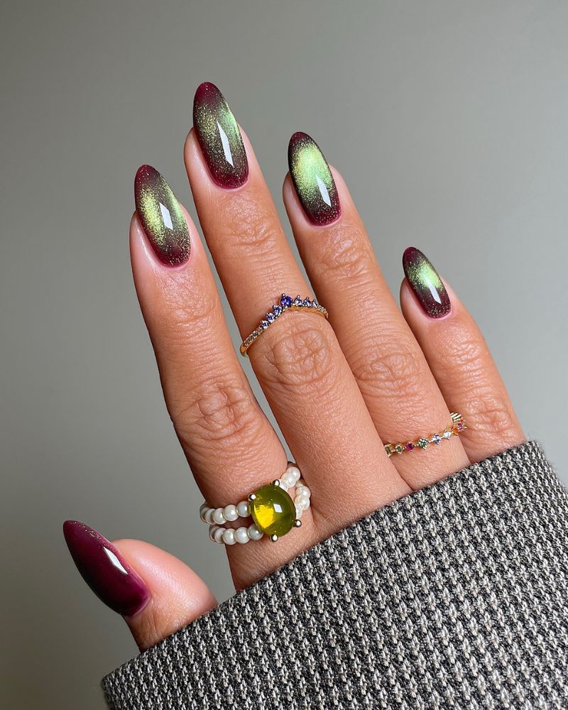 ongles bordeaux avec nail art aura cat eye verte au centre