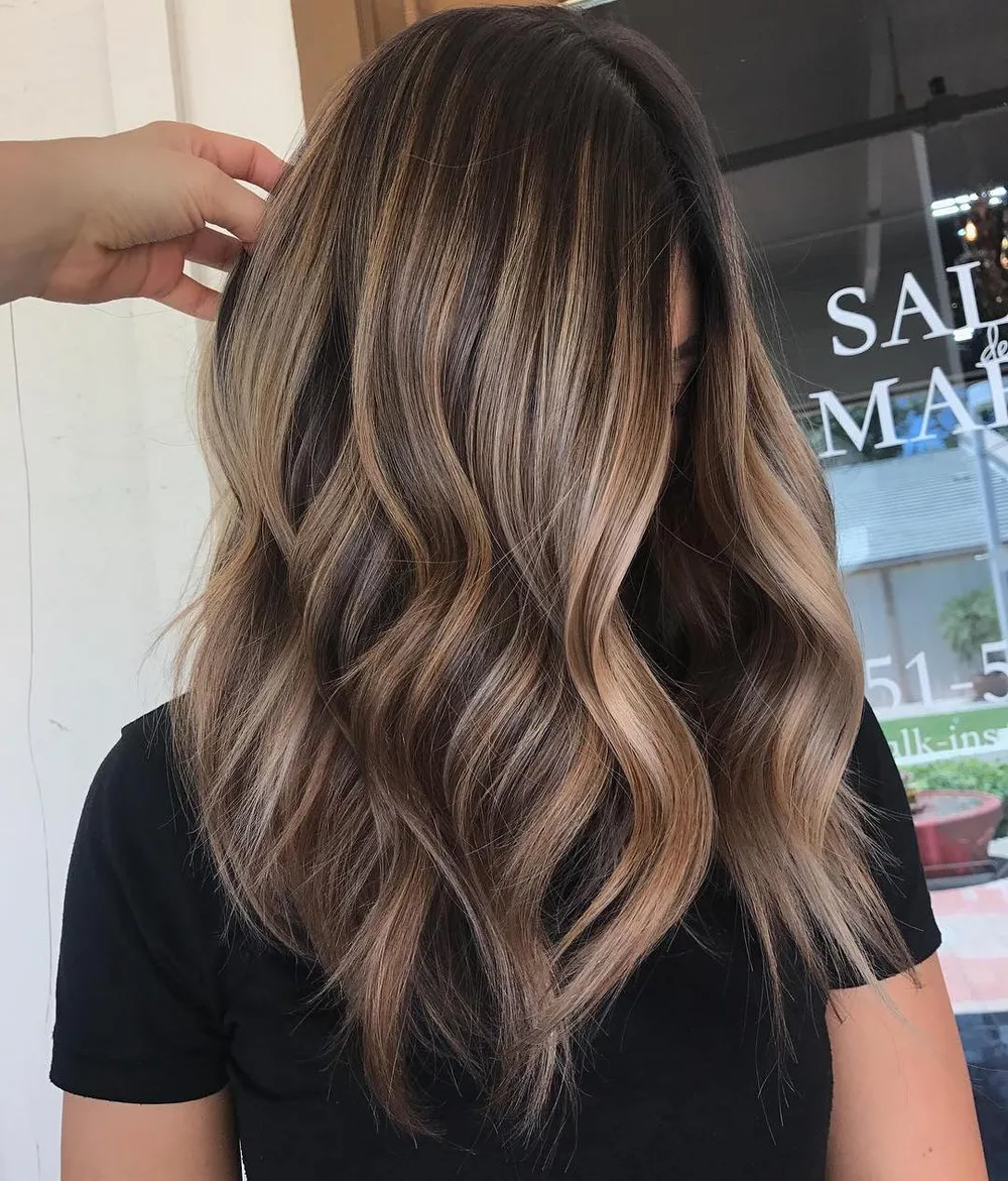 Balayage bicolore base café profonde et mèches caramel sur ondulations