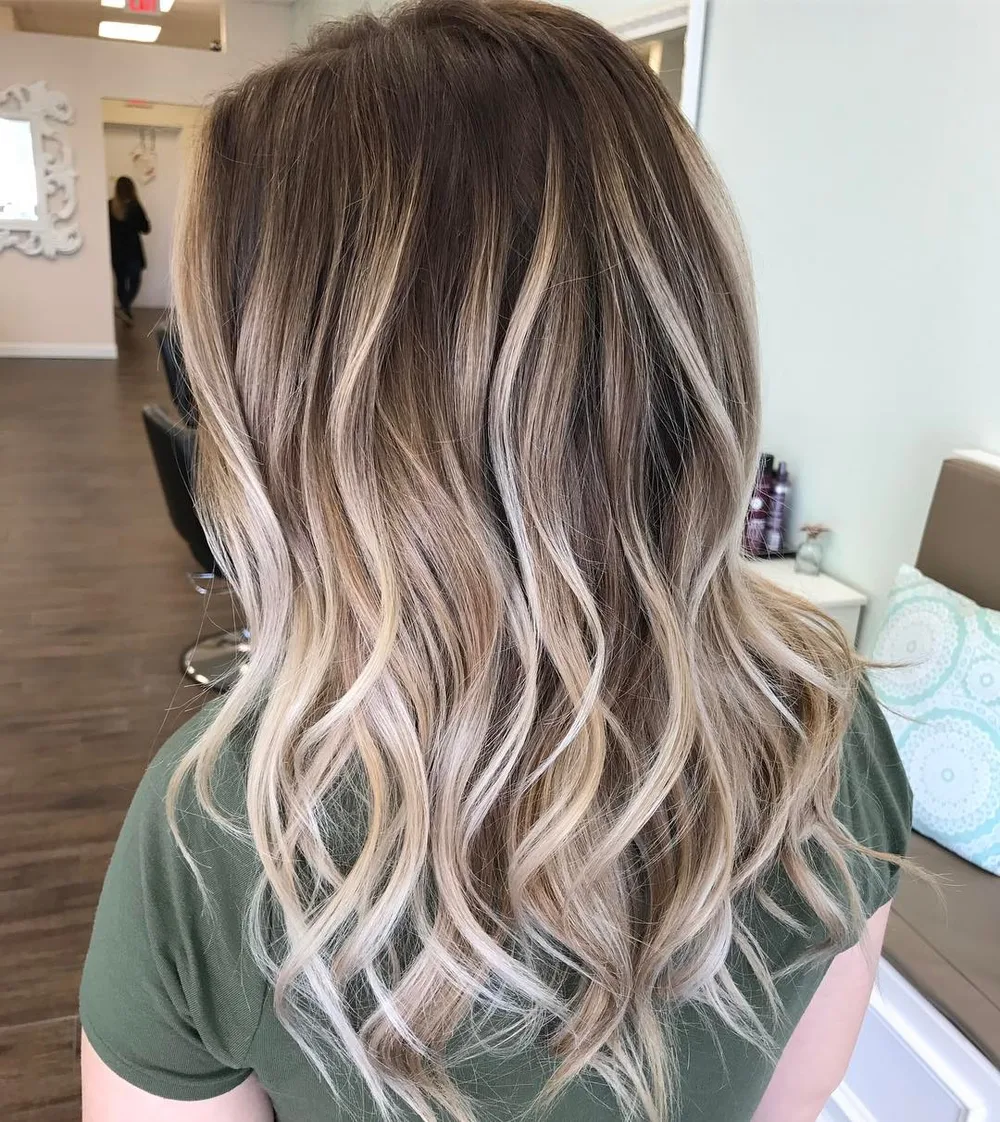 Balayage blond perle nacré aux reflets argentés sur base brune éclaircie