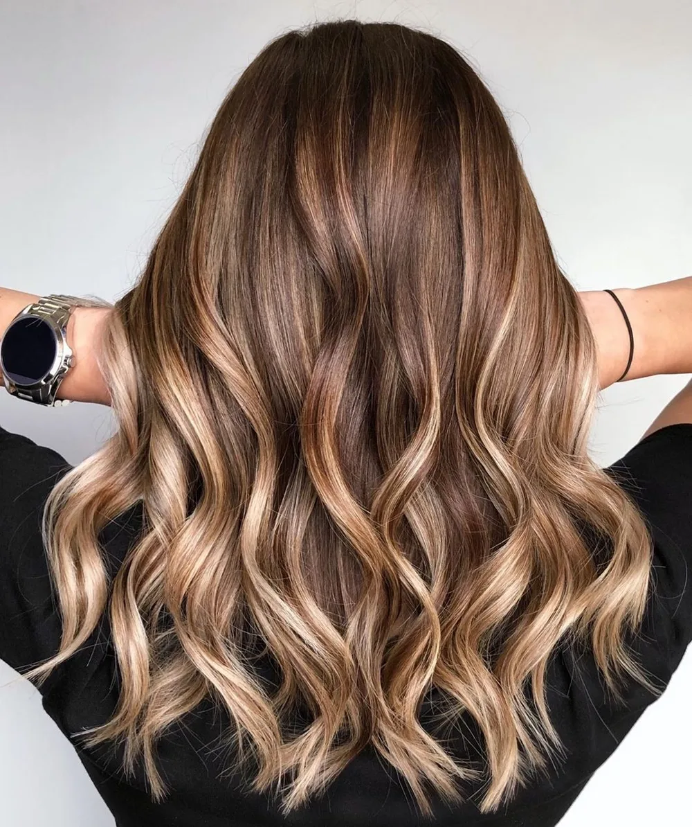 Balayage bronde doré sur longues vagues, reflets lumineux