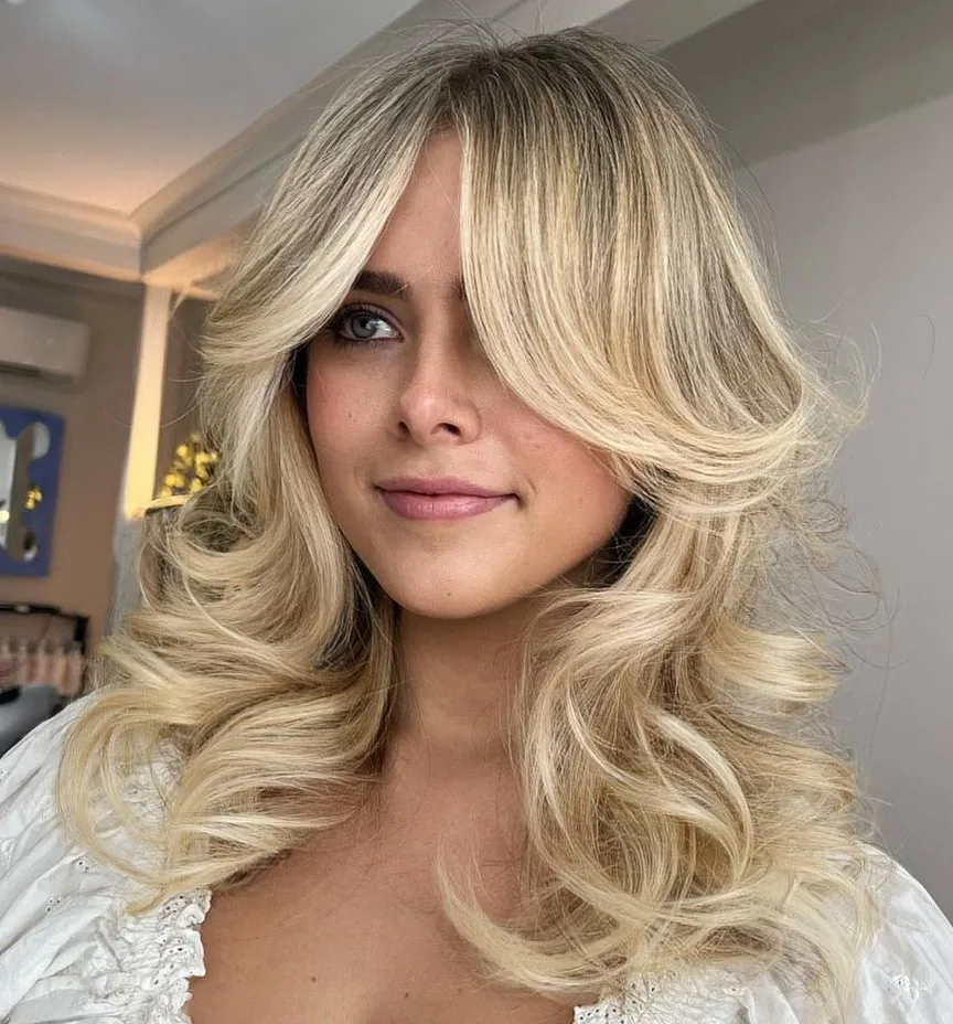 Blond éclatant à babylights avec couches bouclées et butterfly bangs