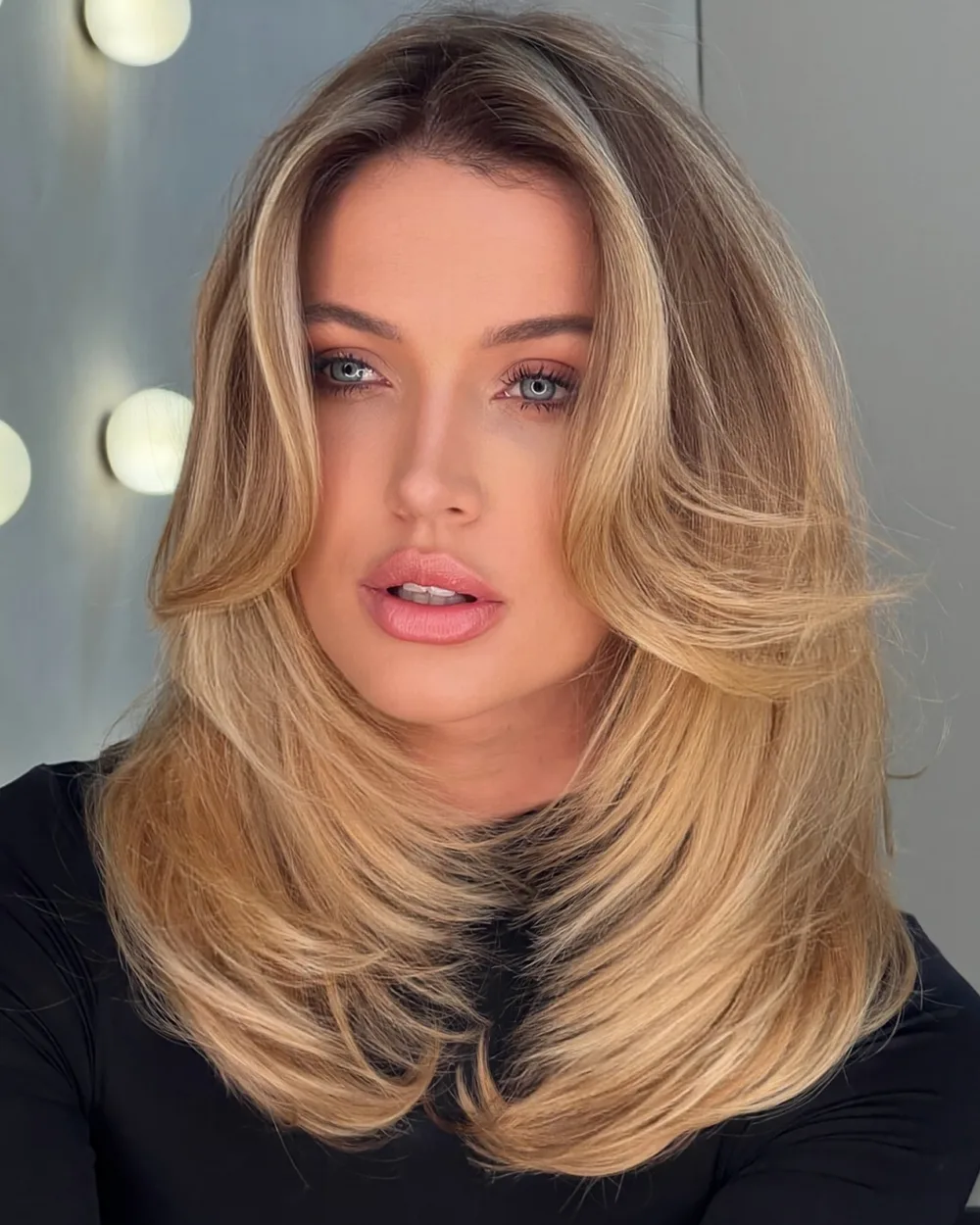 Blond froment fondant en balayage encadrant le visage, yeux bleus