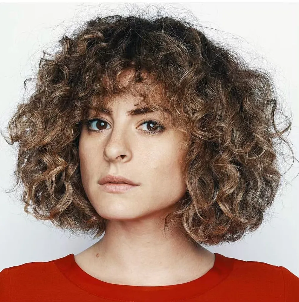 Carré bouclé au niveau du cou avec frange sur cheveux épais frisés