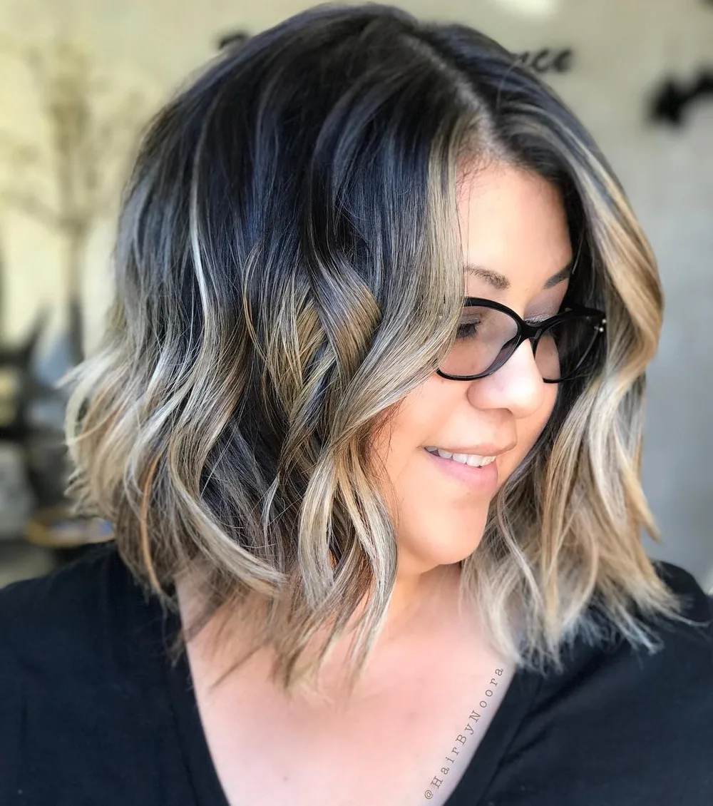 Carré ondulé noir réveillé de mèches blondes en balayage