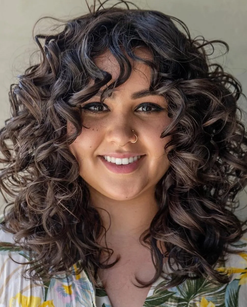 Cheveux bouclés bruns volumineux et définis autour du visage
