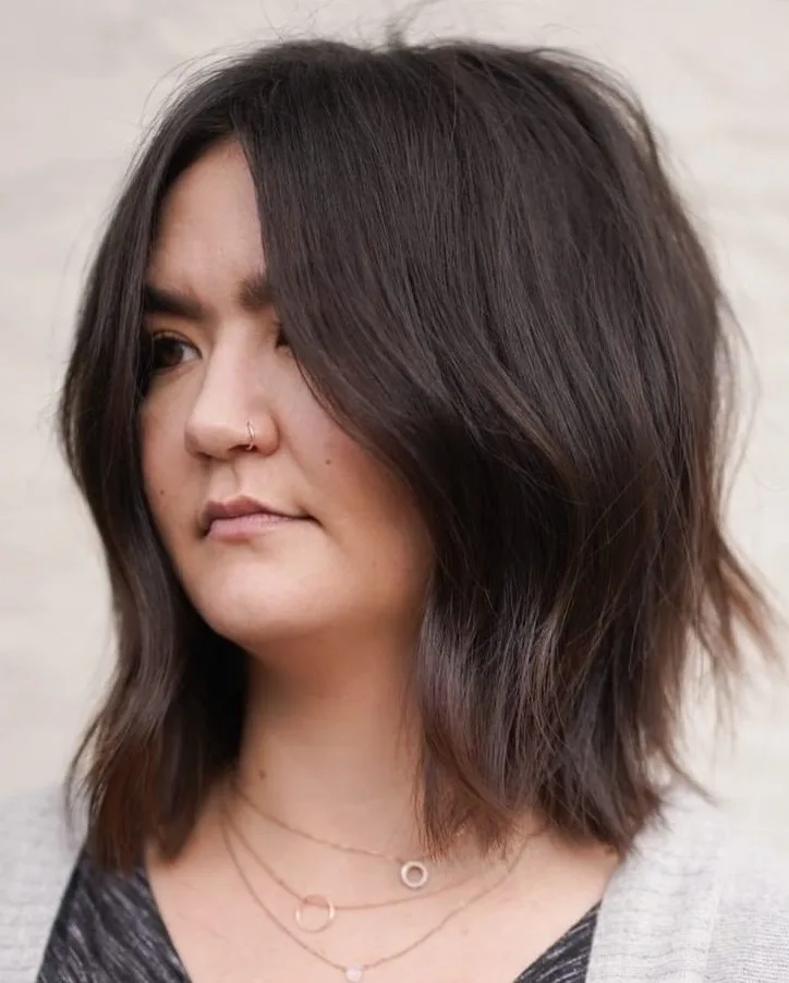 Cheveux bruns mi-longs avec raie au milieu et pointes légèrement recourbées