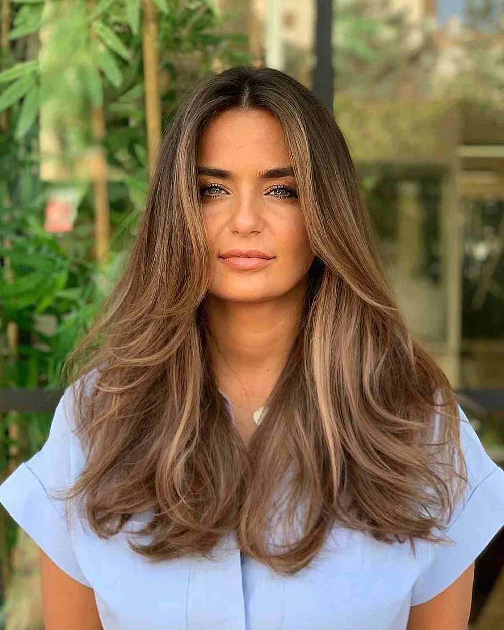Cheveux épais bruns avec mèches et dégradé balayé autour du visage