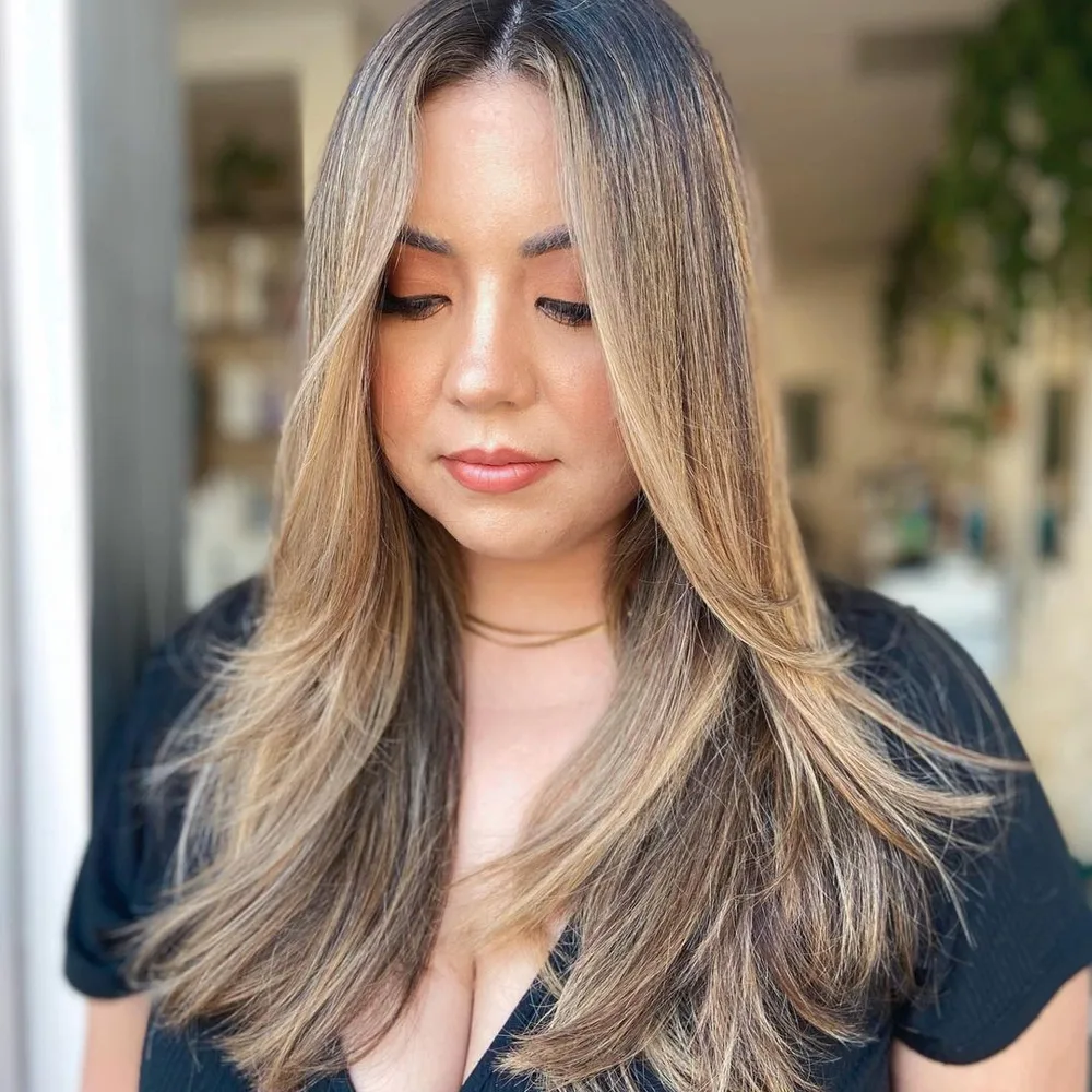 Cheveux longs effilés avec balayage blond et couches encadrant le visage