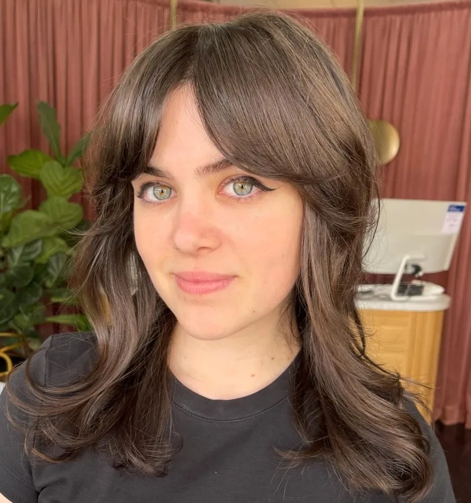 Cheveux mi-longs en vagues souples avec une frange rideau encadrante