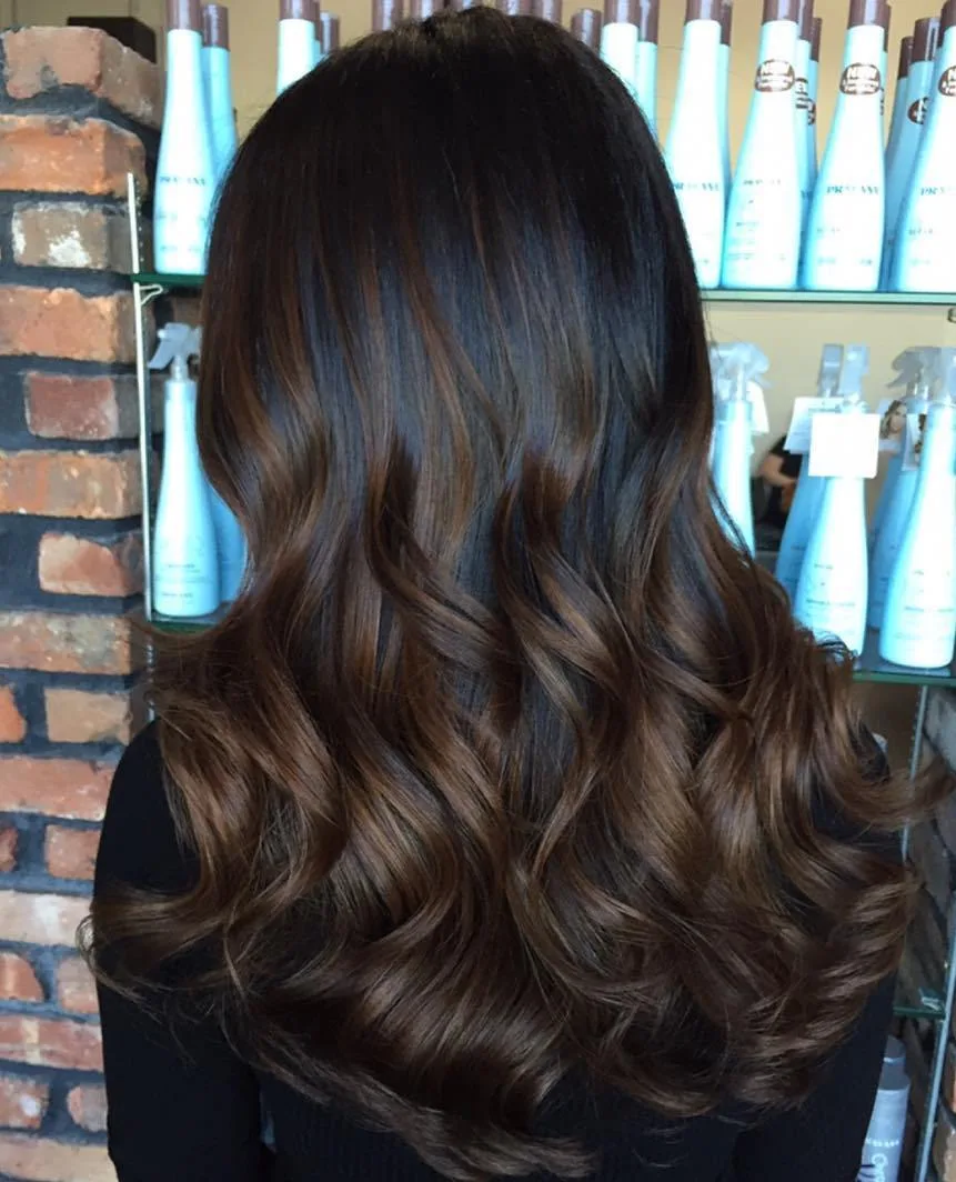 Cheveux noirs avec reflets chocolat brun peints en douceur, longueurs bouclées