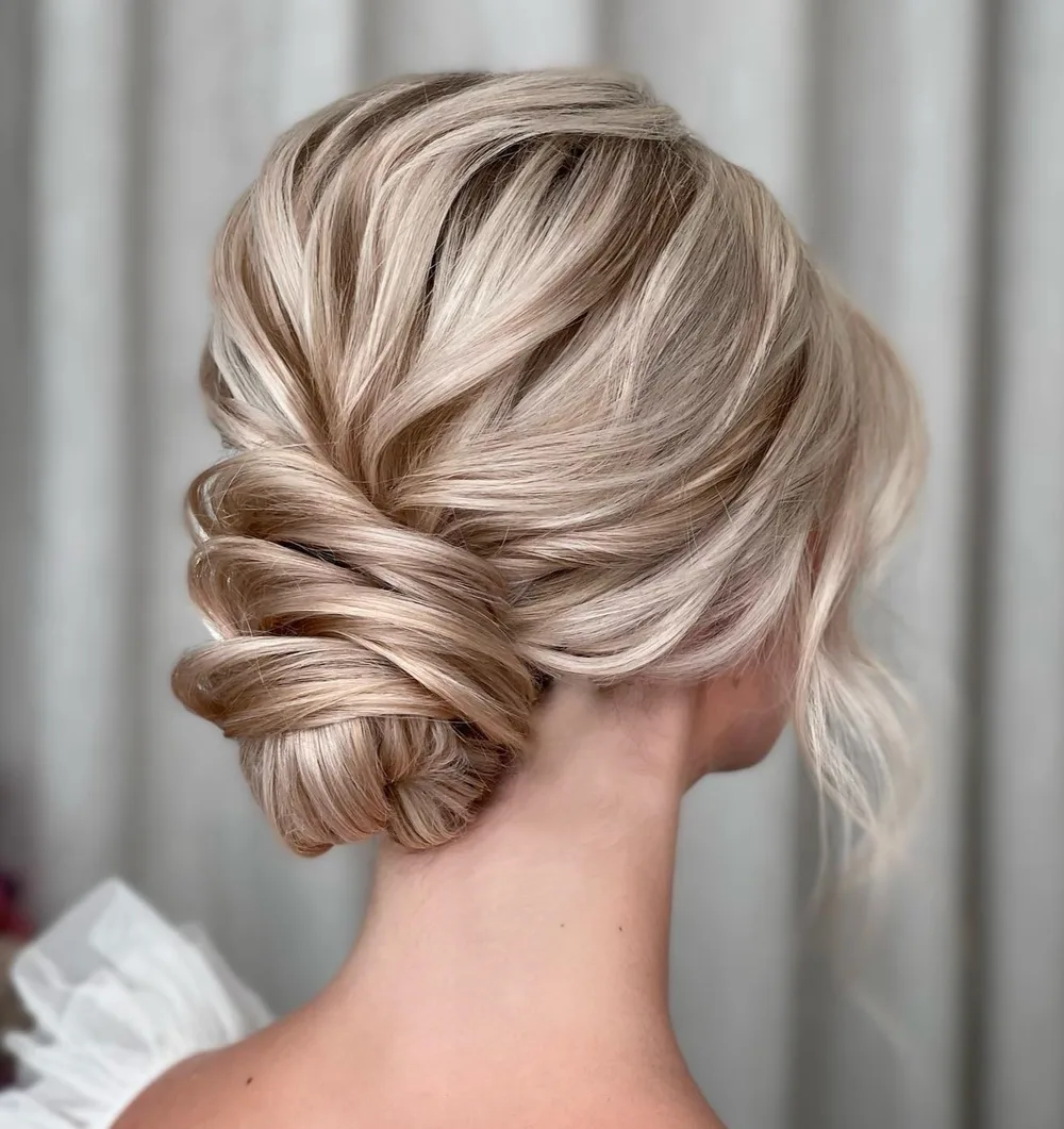 Chignon bas blond aux boucles de cheveux sculptées