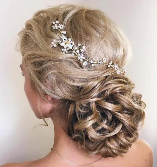 Chignon bas composé de boucles lâchées avec épingle perlée