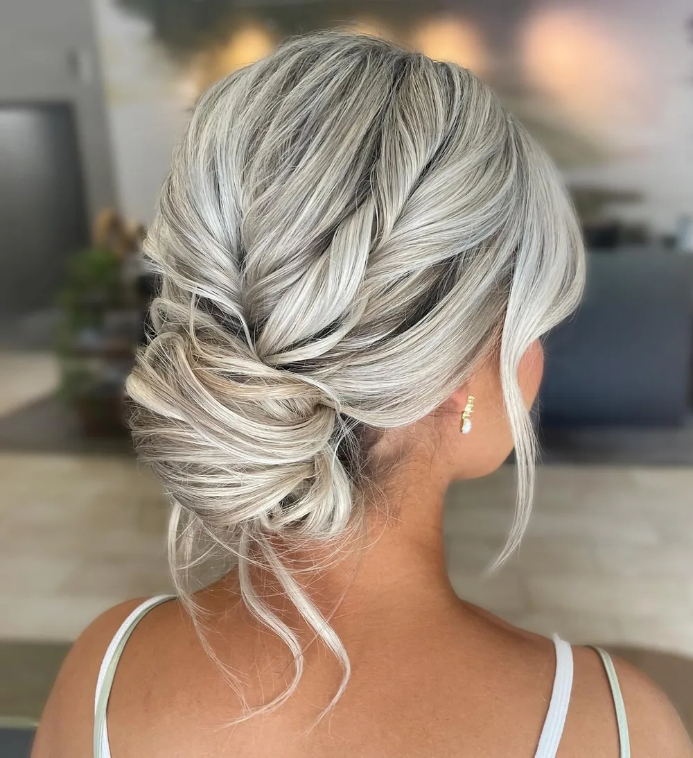 Chignon bas flou blond aux mèches argentées libres