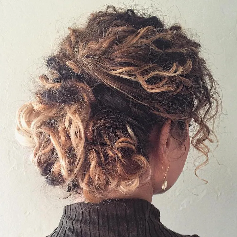 Chignon flou torsadé sur cheveux longs bouclés