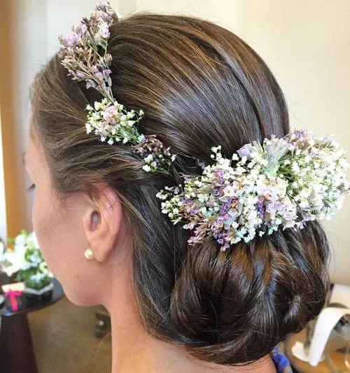 Chignon lisse et net rehaussé de fleurs fraîches sur le côté
