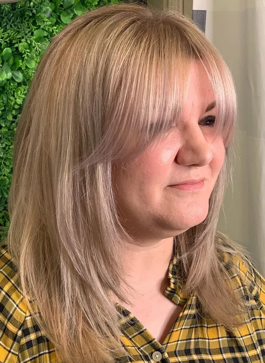 Coupe dégradée blonde mi-longue avec une frange rideau encadrante