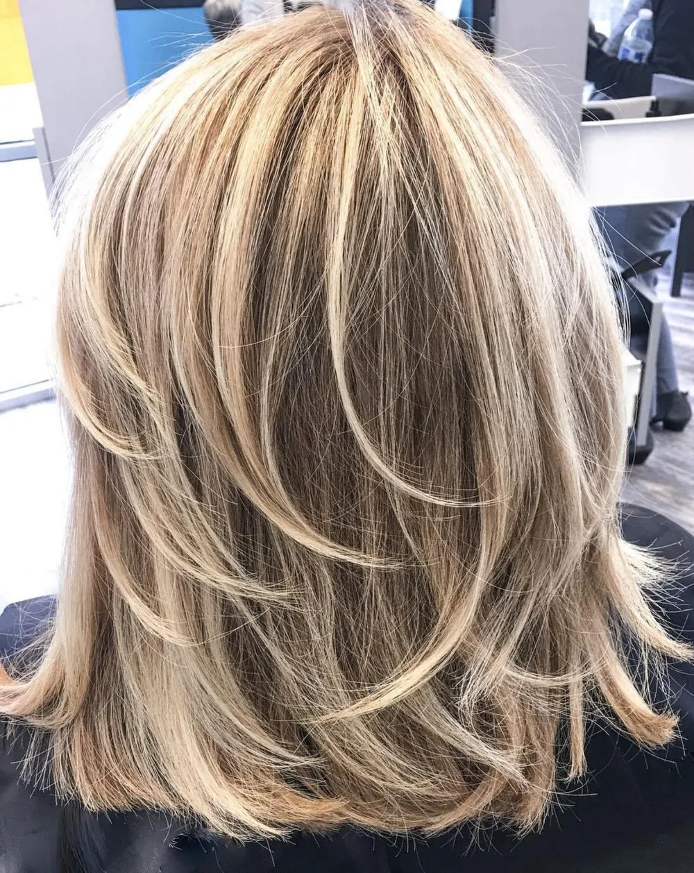 Coupe mi-longue blond multi-tons avec couches plumeuses effilées