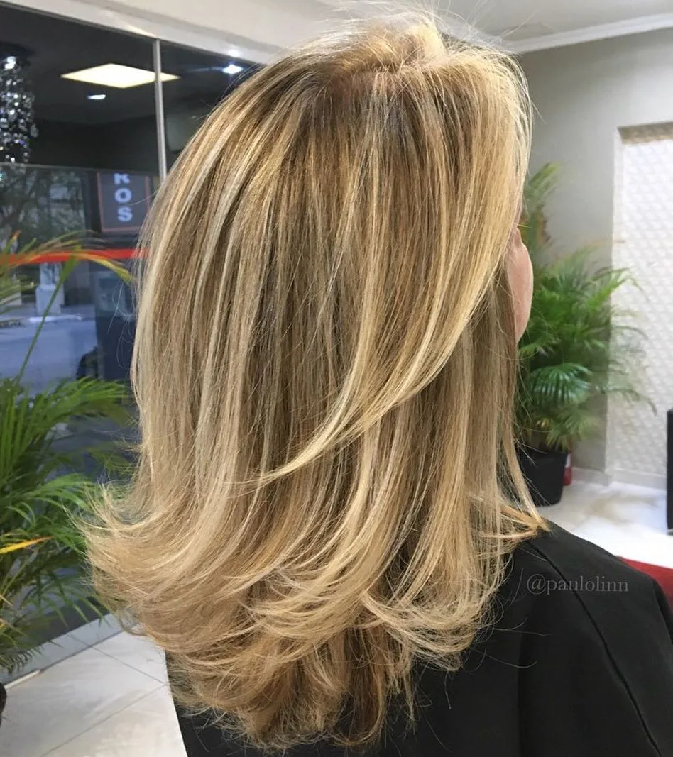 Coupe mi-longue blonde à couches avec pointes flippées vers l'extérieur