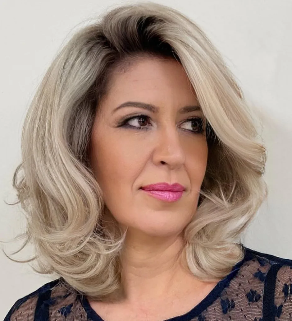 Coupe mi-longue blonde à racines foncées et brushing volumineux