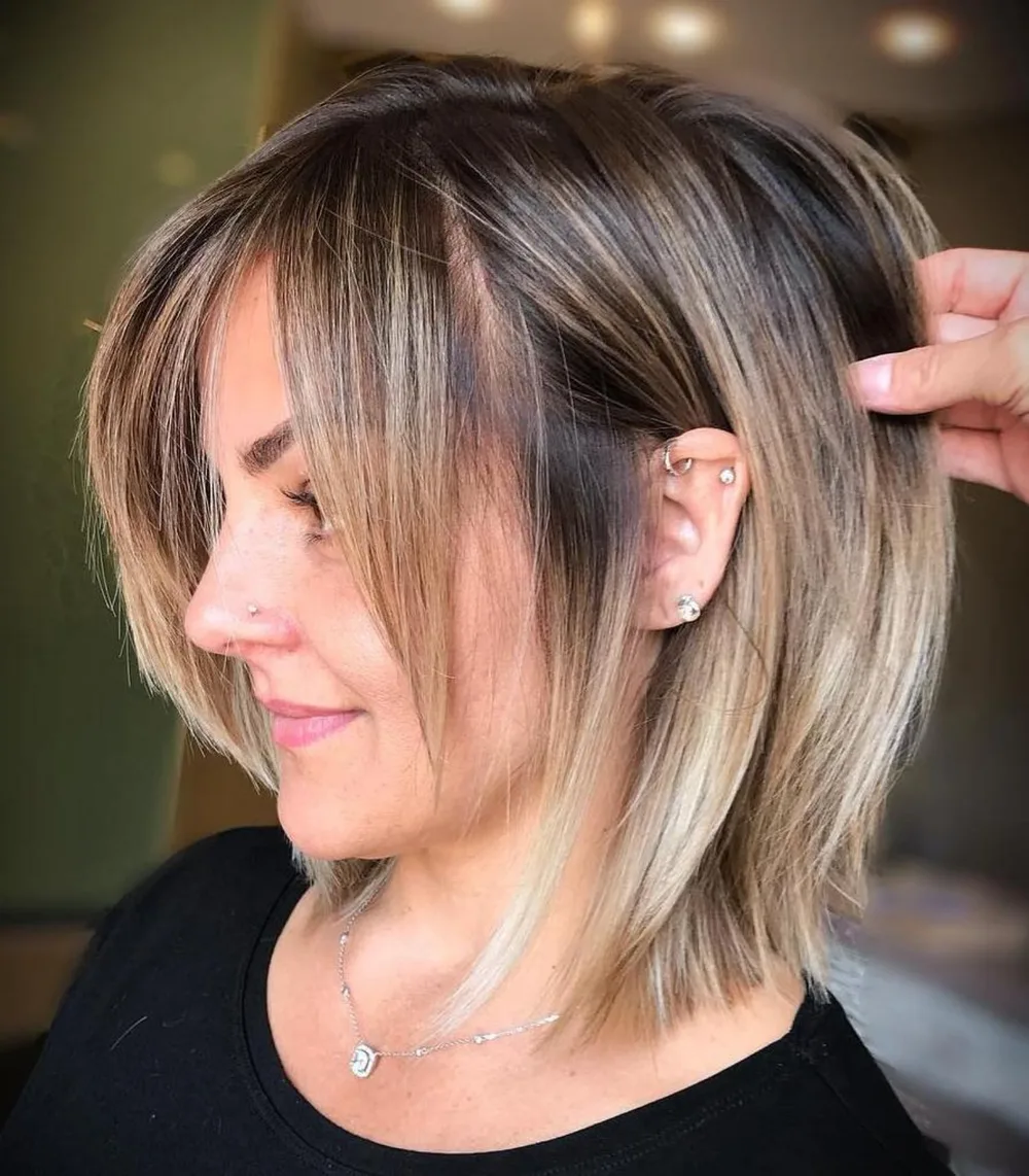 Coupe mi-longue bronde avec frange angulaire qui s'allonge vers les côtés