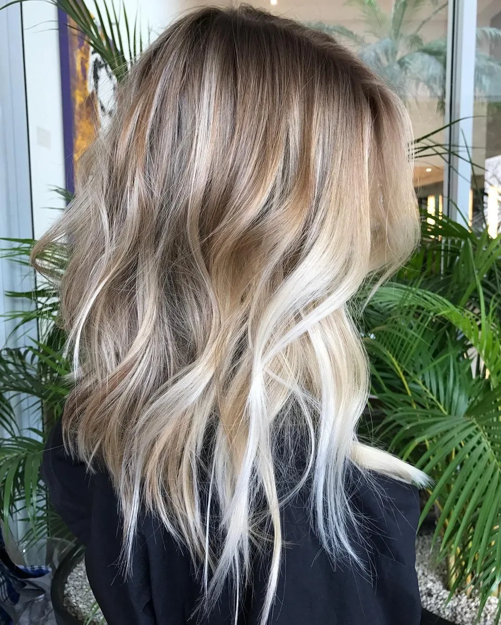 Coupe mi-longue droite coiffée en beach waves avec balayage clair