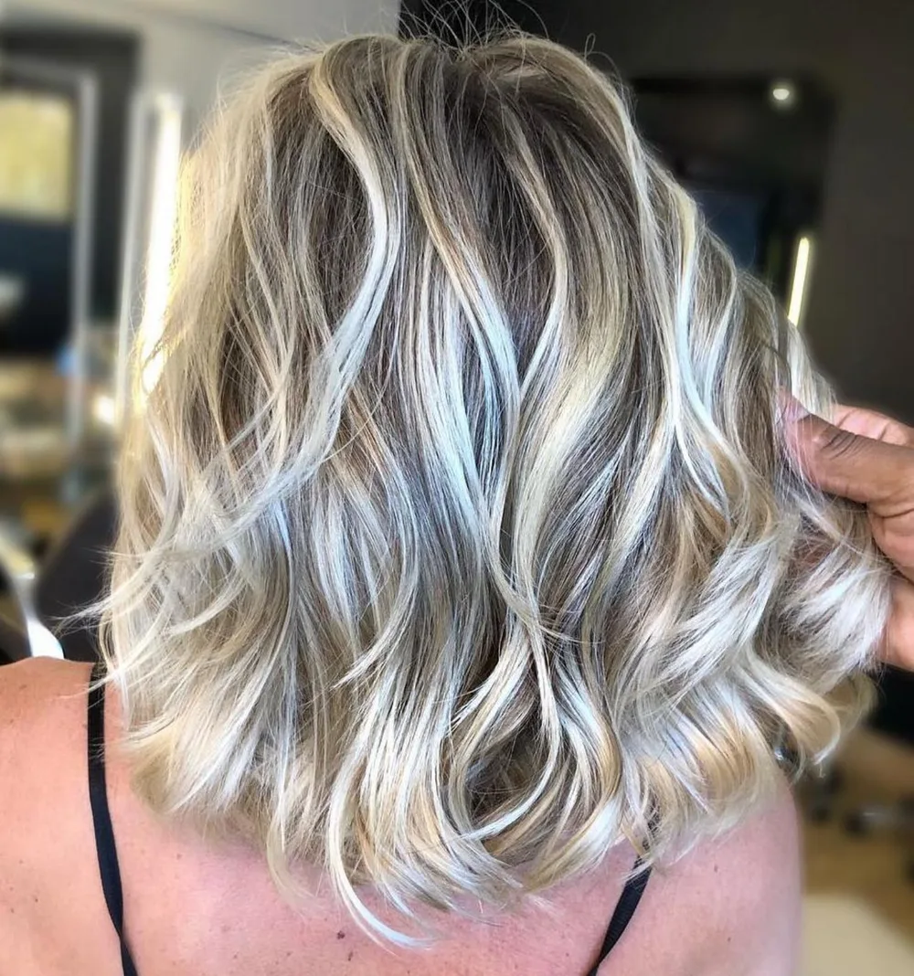 Coupe mi-longue en vagues avec base cendrée et reflets blonds vifs