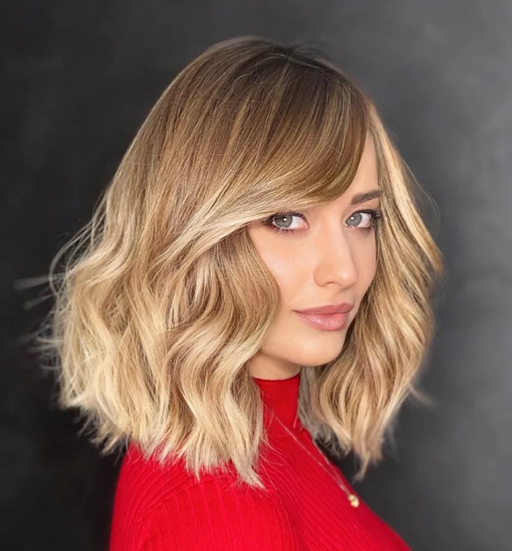 Lob évasé ondulé avec frange balayée sur le côté et balayage miel
