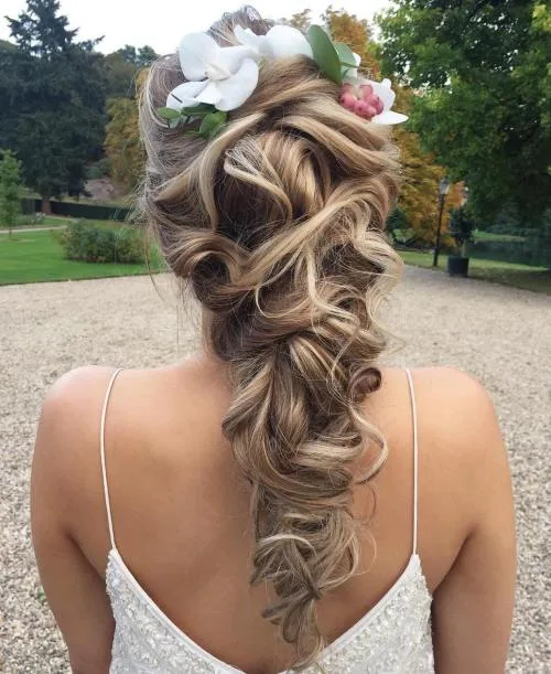 Longues boucles laissées libres avec une fleur sur le côté