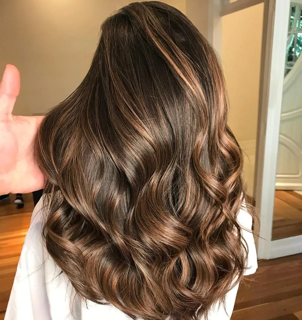 Balayage caramel-brun à éclat métallique sur cheveux épais, raie trois-quarts