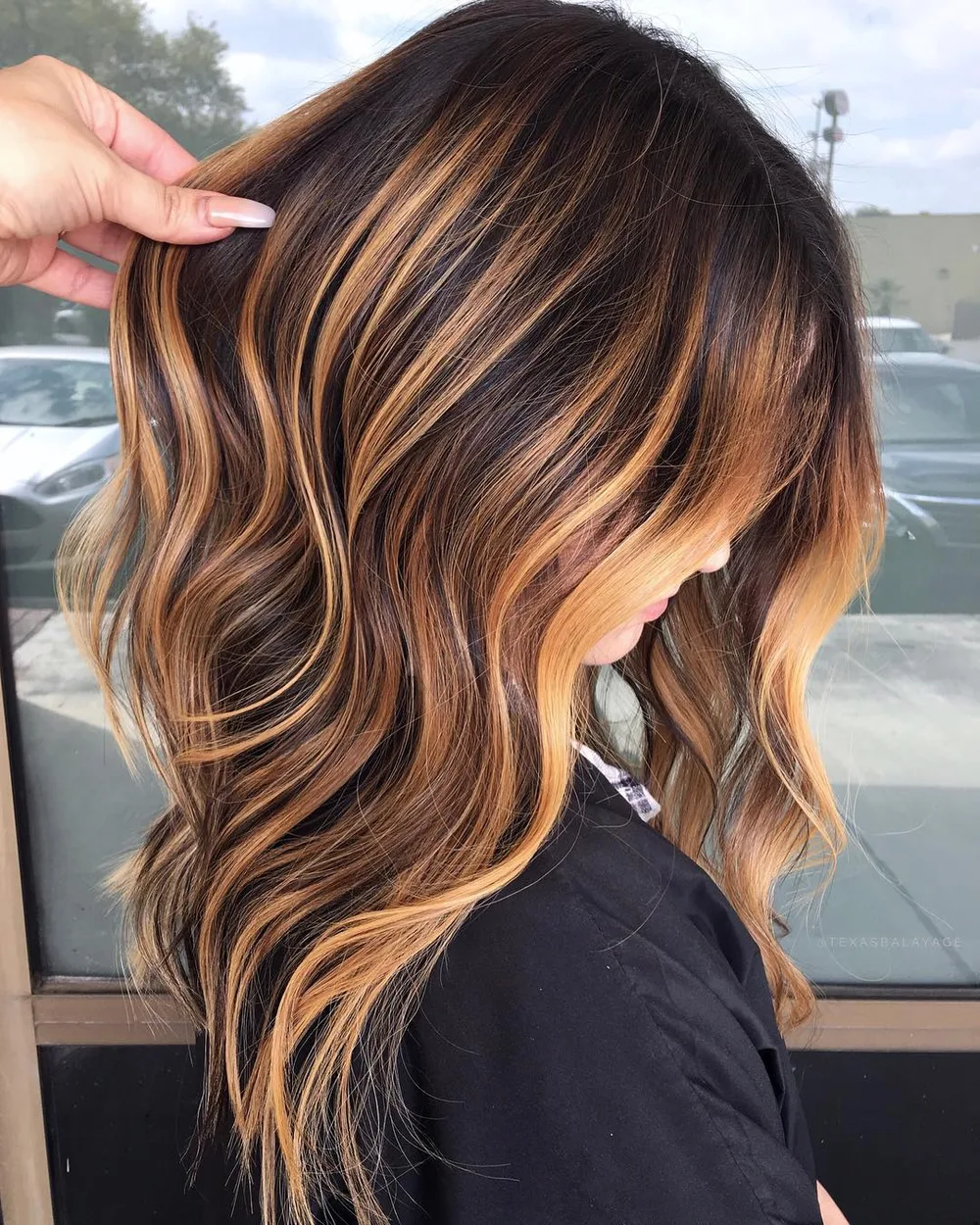 Balayage caramel chaud sur base foncée avec root melt et vagues, raie au milieu