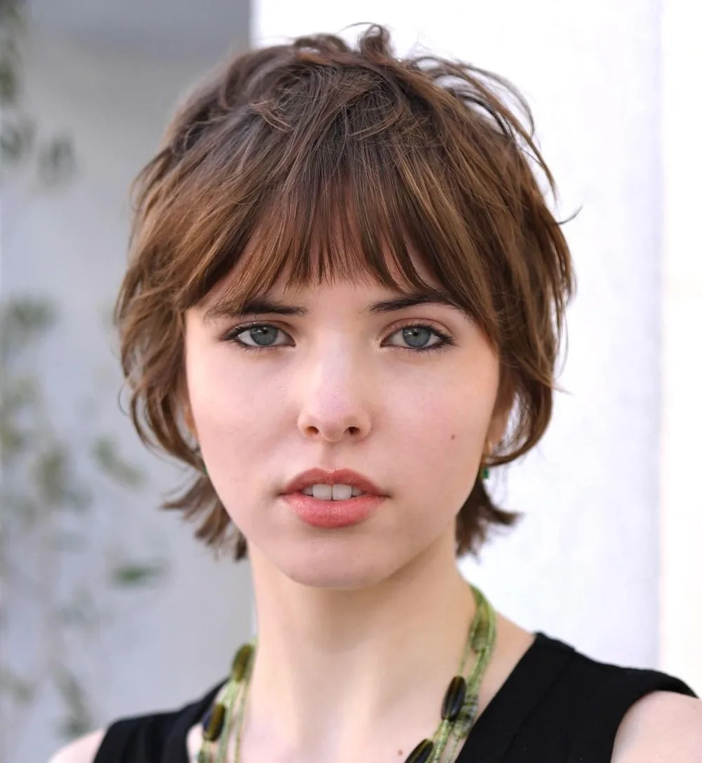 Bixie shaggy inspiré des années 90 avec micro bangs, visage rond