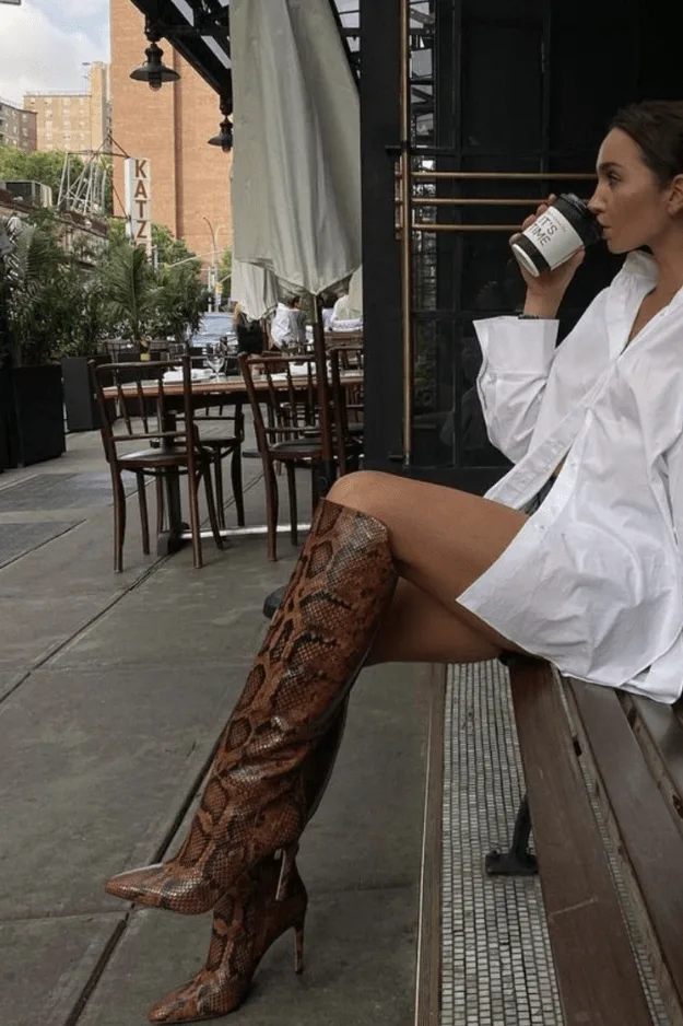Bottes hautes imprimé python à talon portées avec une chemise blanche