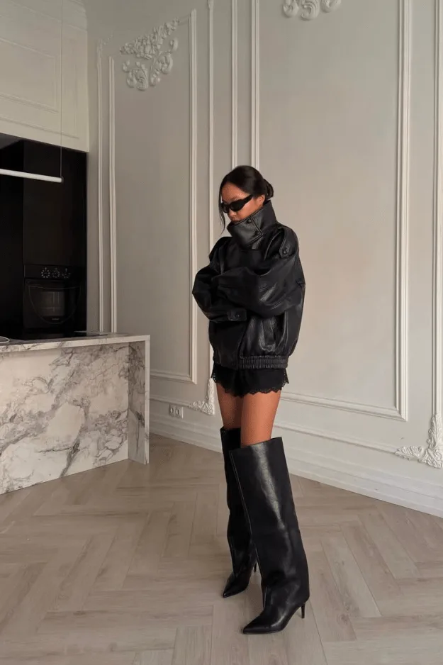 Bottes hautes noires à talon portées avec une veste en cuir