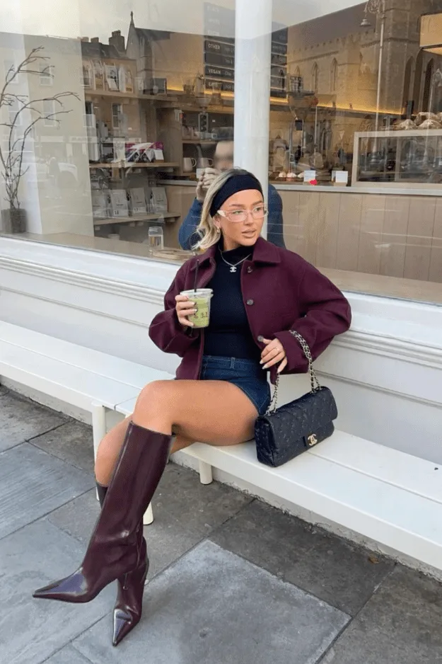 Bottes hautes oxblood pointues portées avec un short et une veste bordeaux