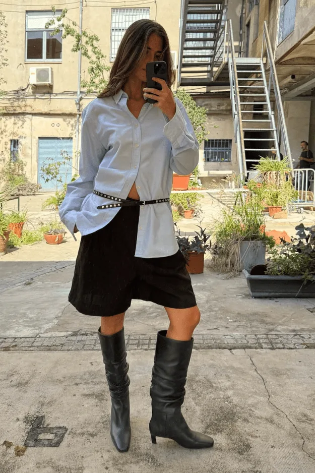 Bottes noires à talon kitten portées avec une chemise blanche et une jupe