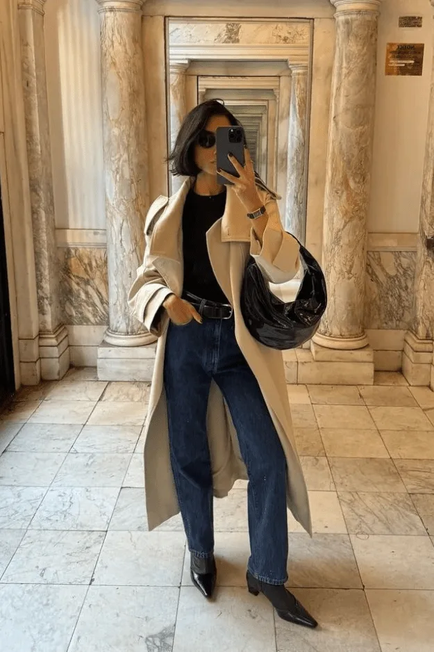 Bottes noires à talon portées avec un jean brut et un manteau long