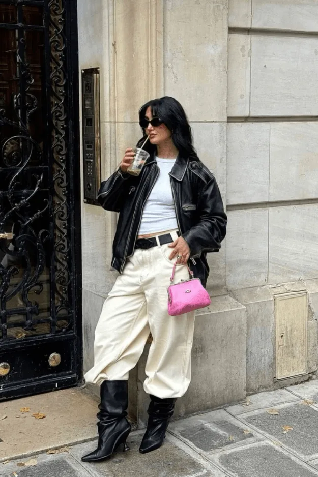 Bottes slouchy noires portées avec un pantalon crème et une veste en cuir