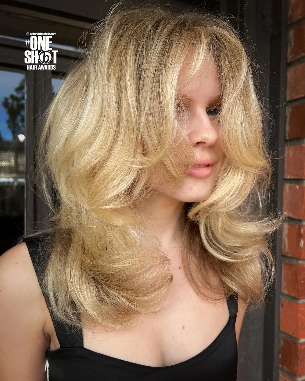 Butterfly cut avec grandes boucles volumineuses et couches encadrantes sur blond chaud