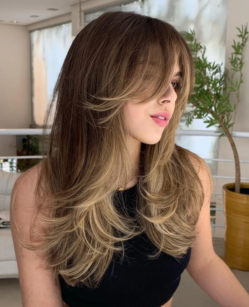 Butterfly cut long avec couches wispy effleurant les pommettes et brushing volumineux